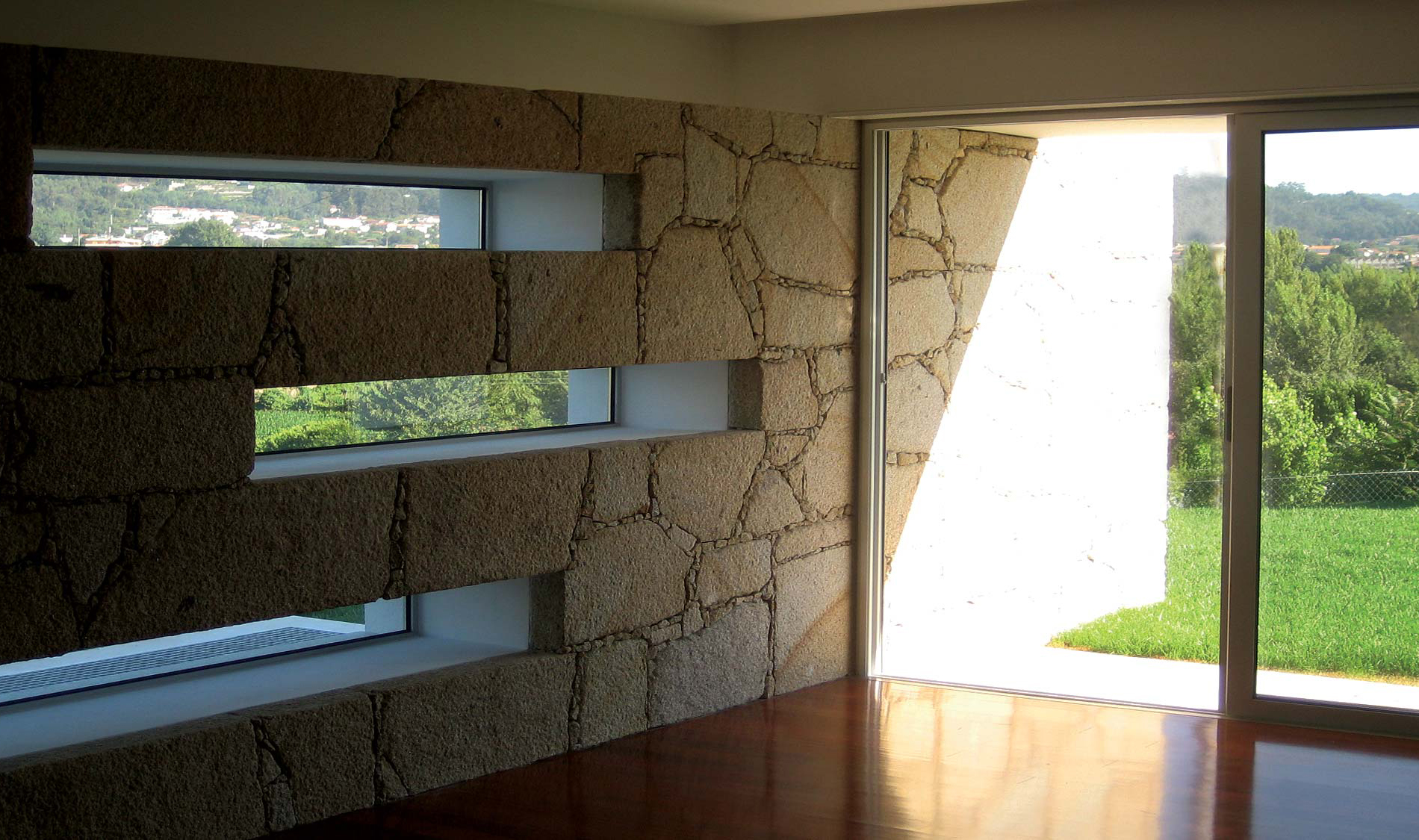 Pedra de granito ou mármore, qual escolher? Sala de estar da Casa da Oliveira. que tem parede de granito amarelo. Projeto Obra Atelier